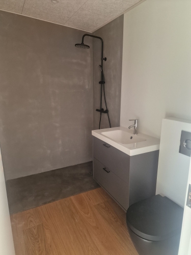 Microcement badeværelse med mørke vægge og bruseområde