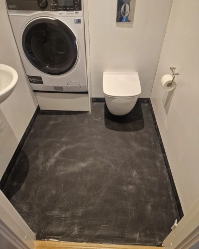 Microcement badeværelse med mørkt gulv og væghængt toilet